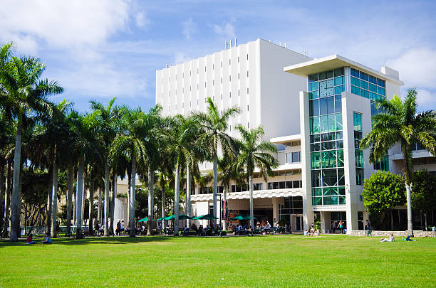 Richter Library and clock tower at University of Miami "Coral Gables, United States - February 21, 2012: People sit on a grassy lawn while others walk around nearby outside the Otto G. Richter Library and the Dr. Maxwell and Reva B. Dauer Clock Tower at the main University of Miami campus in Coral Gables." university of miami stock pictures, royalty-free photos & images