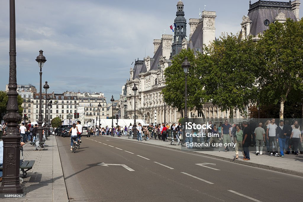 People Walking Across the Bridge Pont d'Arcole, Paris, France "Paris, France - September 19, 2009: Parisians and tourists walking on the bridge Pont d'Arcole on sunny saturday afternoon. Further to the right is seen l'Hotel de Ville ( Paris City Hall) located on the Place de l'Hotel de Ville (City Hall Plaza) in the 4th arrondissement of Paris. Before 1802 this public square was called the Place de Grave." Activity Stock Photo