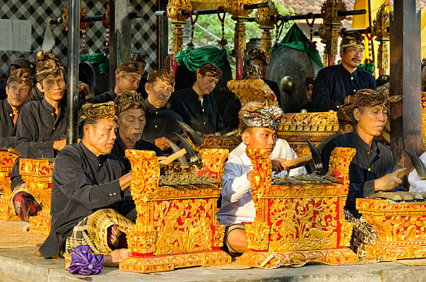 Gamelan orchestra at a Hindu ceremony in Bali "Tejakula, Bali Indonesia - March 28, 2013: Men playing in a Gamelan orchestra at sunset. The instrument, they play calls Saron. Similar to a xylophone. It will played by a hammer. This orchestras playing at ceremonys in hindu temples. Photo taken in Tejakula - Temple Bale Agung - in North Bali - Indonesia." mahabharata stock pictures, royalty-free photos & images