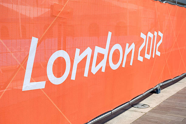 London 2012 Olympic Games Banner "London, United Kingdom - 23rd July 2012. Long orange banner with section of the London 2012 Olympic Games logo. This long banner is attached to special fencing which surrounds the Excel Building in East London where part of the Olympic Games will be held." 2012 stock pictures, royalty-free photos & images