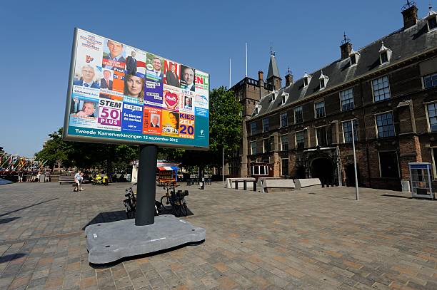 Billboard with election posters in The Hague "The Hague, the Netherlands - August 19, 2012: Billboard with election posters near the Binnenhof (to the right) in The Hague. The Binnenhof is the courtyard of the Dutch Parliament, the center of politics in the Netherlands. The elections for the House of Representatives are held on September 12, 2012. At the background there is a small group of people standing together (far left) and two people walking by in the direction of the Binnenhof." binnenhof photos stock pictures, royalty-free photos & images