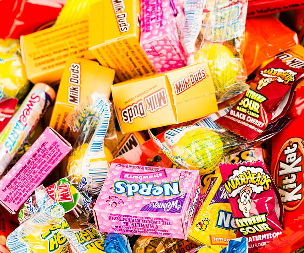 Assorted candies in a glass jar on a white background. View from above.