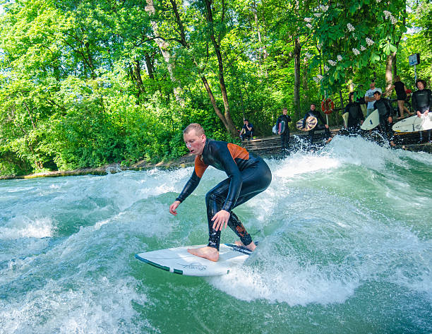 Munich, Germany - November 9, 2021: A surfer rides the swell on the Eisbach River. The Eisbach flows through the Englischer Garten and is a tributary of the Isar River.