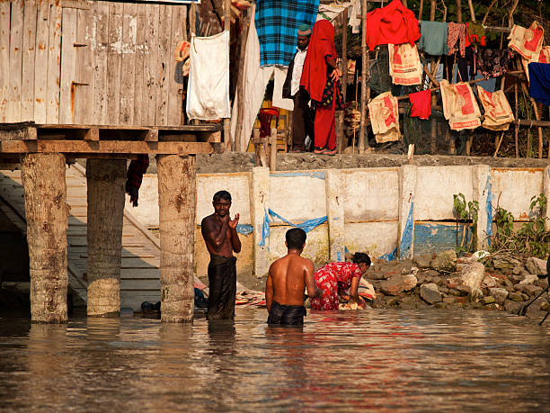 Everyday life in Bangladesh "Khulna, Bangladesh - January 28, 2012: Group of local people washing themselves in the river at the end of the day. Photographed in late afternoon sunlight." brahmaputra river stock pictures, royalty-free photos & images