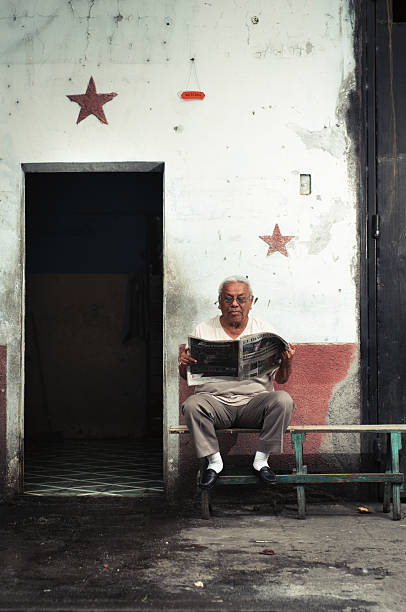 Senior man sitting on bench and reading a newspaper in the park