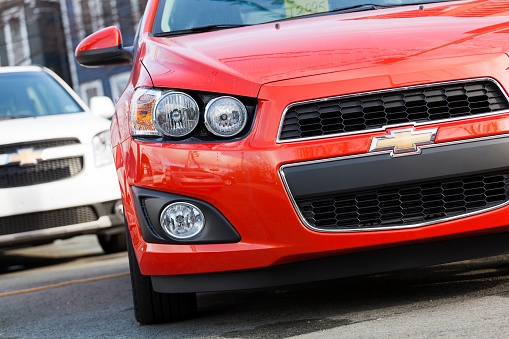 Halifax, Nova Scotia, Canada - December 13, 2011: At a car dealership, a 2012 Chevrolet Sonic front view with another Chevrolet compact vehicle behind.  Price tag in front window partially visible.  The Sonic replaced the Chevrolet Aveo in North America and was met with a much stronger market appeal.  The revised headlights, larger wheels, revised interior, and overall more aggressive design makes the Sonic a welcome replacement to the bland Aveo.