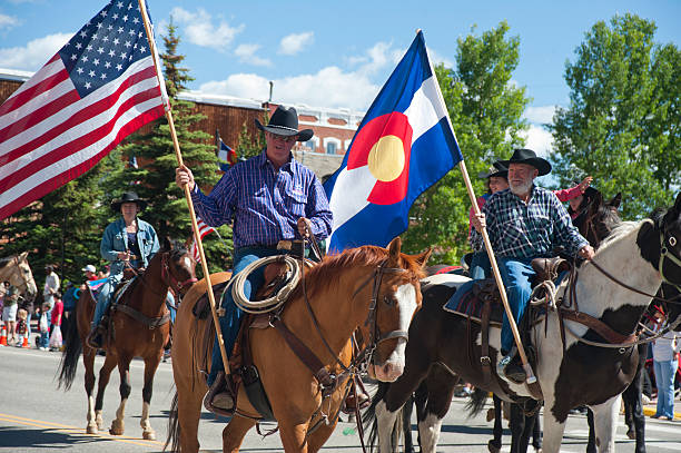 Fourth of July Parade Entry "Leadville, United States - July 4, 2010: A Fourth of July parade entry in Leadville, Colorado includes two cowboys on horses carrying the American flag and the state flag of Colorado down the main thoroughfare." leadville stock pictures, royalty-free photos & images