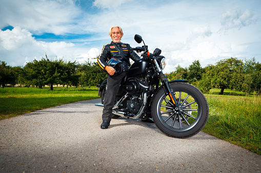 Pensive mature man leaning on motorcycle when waiting for girlfriend outside