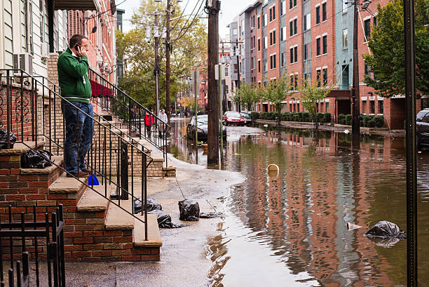 Hurrican Sandy: man talking on the phone near flooded street "Hoboken, New Jersey, USA - October 31, 2012: Man talking on the phone on a stoop on a flooded street" hurrican stock pictures, royalty-free photos & images