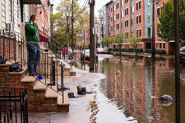 hurrican sandy: homem a falar ao telefone rua perto inundada - hurrican imagens e fotografias de stock