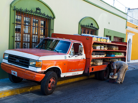 Mazatlan, Mexico - December 11, 2008: Pickup truck loaded with drinks stops at the side of the road in the historical centre. A man can be seen bending down to pick up a crate of bottles.
