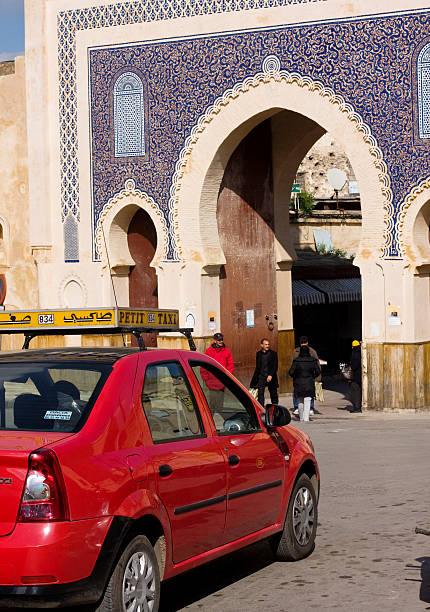 Bab Boujeloud gate, Fez, Morocco "Fez, Morocco - February 6, 2013: A petit taxi parked in front of famous Bab Boujeloud gate of Medina of Fez in Morocco. Red Petit Taxi is a small car used in Morocco for transportation. Two main types of taxis in Morocco are grand taxis and petit taxis." bab boujeloud stock pictures, royalty-free photos & images