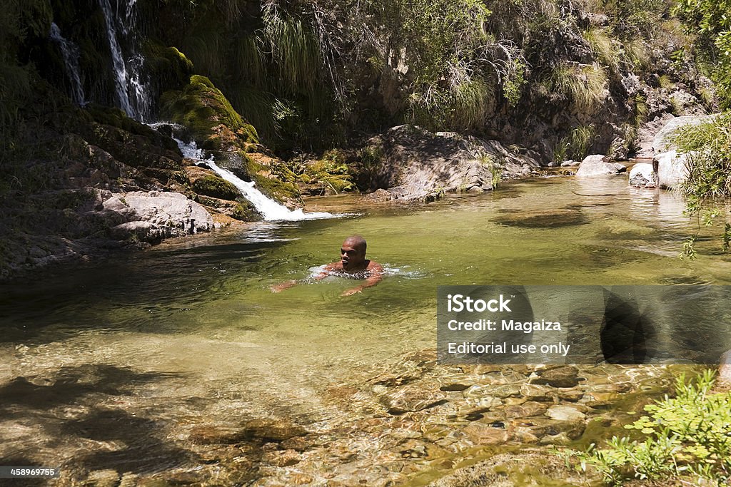 Swimming in the waterfall "Merlo Village, San Luis Province, Argentina - January 02, 2013: A man in vacation swims in the natural pool of a waterfall." Adult Stock Photo