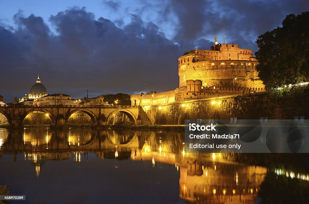 Rome in dusk "Rome, Italy - October 12th, 2012: Castel Sant'Angelo (Mausoleum of Hadrian, on the right) and the Ponte Sant'Angelo (Aelian Bridge, on the left) in dusk, over a dramatic cloudy sky, mirrored in Tiber. In the background on the left Saint Peter's basilica dome. Horizontal image" Architectural Dome Stock Photo