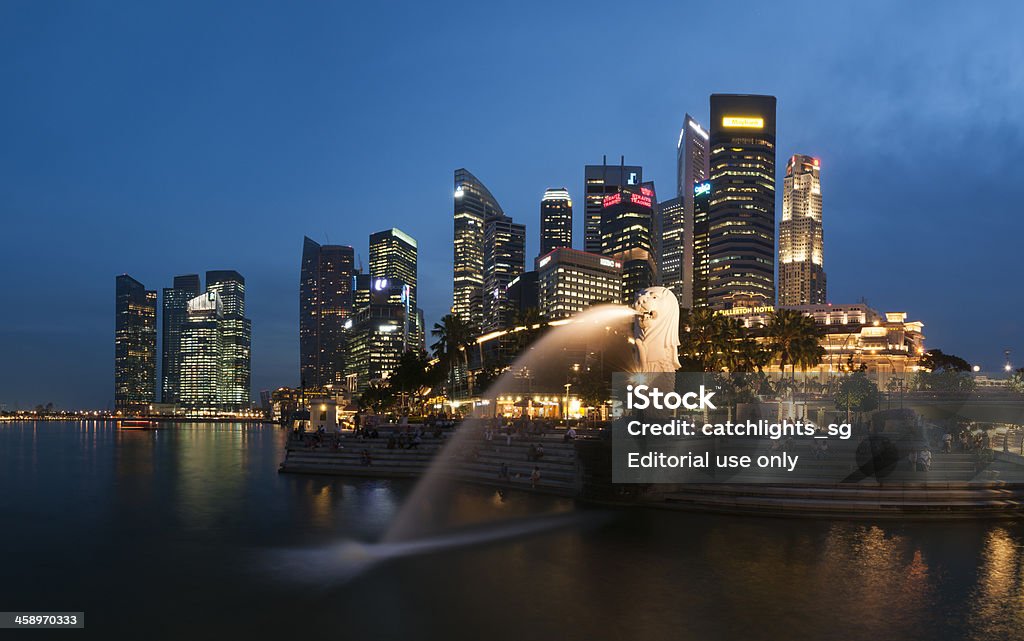 Merlion Park in Panorama "Singapore, Singapore - May 16, 2012: Tourists sitting at the steps of Merlion Park, enjoy the night scene of Marina Bay. A very popular view of Merlion during dusk hour with Centre Business District in background in panorama." Singapore Stock Photo