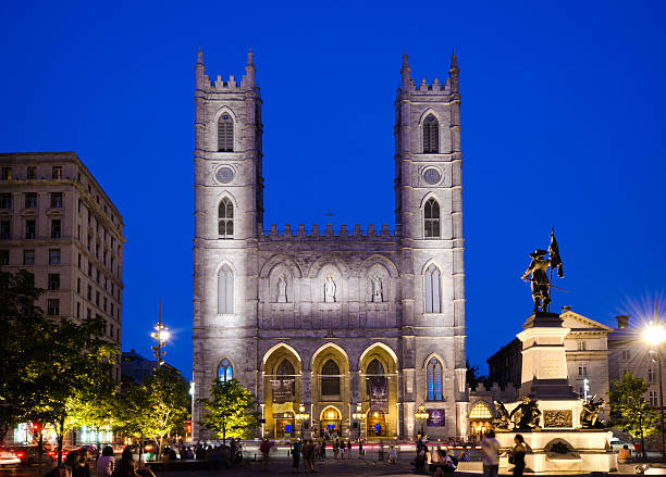Montreal, Canada - August 25, 2012: People spend time in Place d'Armes in the Old Montreal section of Montreal with the Maisonneuve Monument and Notre-Dame Basilica nearby. 