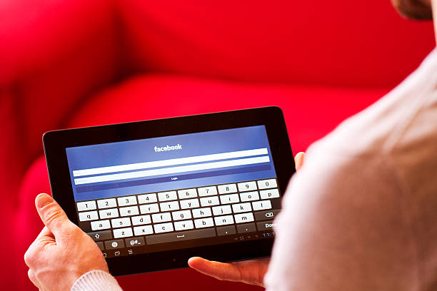 facebook-homepage angezeigt auf ein tablet. - men iphone internet social networking stock-fotos und bilder