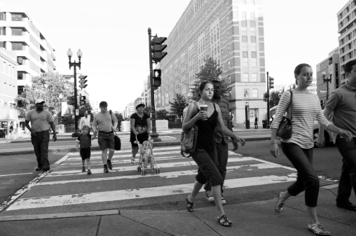 Washington DC, USA - June 15, 2012: Pedestrians at Dupont Circle cross the street at a crosswalk. Black and Caucasian, a family pushing a baby stroller, and a young woman with coffee are among the pedestrians.