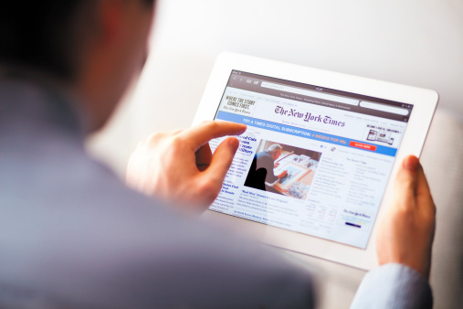 Nizhnevartovsk, Russia - March 11, 2013: Man touching The New York Times website to iPad. The New York Times is an American daily newspaper, founded and continuously published in New York City since 1851. iPad product by Apple Inc.