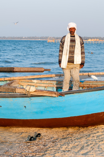 Fayoum, Egypt - March 1, 2011: An Egyptian man stands in his fishing boat at the end of a day beside Lake Quran in the Fayoum, Egypt