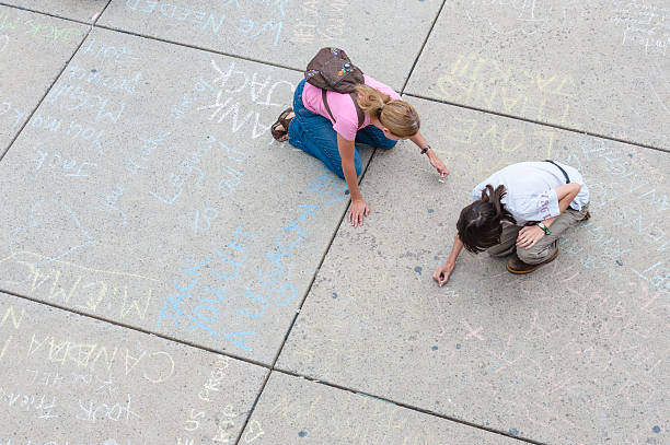 Jack Layton's Chalk Memorial "Toronto, Canada - August 26, 2011: Women drawing messages in chalk outside of City Hall in Toronto, as part of a public memorial to NDP leader Jack Layton after his death on August 22, 2011." ndp stock pictures, royalty-free photos & images