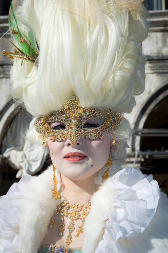 A golden carnival mask for festivals and performances with blue and red feathers around it