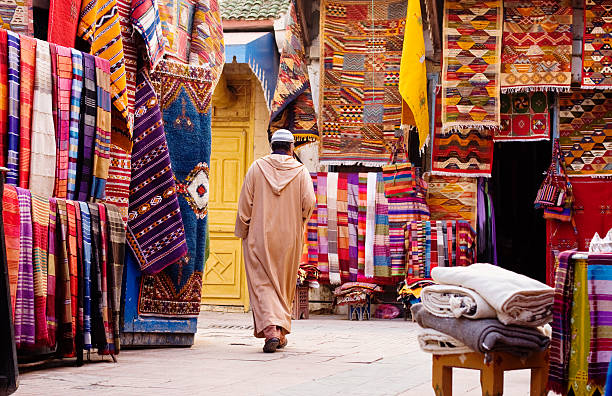 Moroccan man passing by the carpet sellers, Morocco stock photo