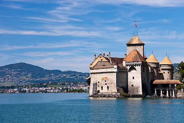 Chillon Castle Veytaux, Switzerland - July 31, 2012: This photograph of Chillon castle on the shores of Lake Geneva near Montreux (in the background) was taken from a passing cruise ship around noon on a summer day. The oldest written document mentioning the castle dates from 1150. Some tourists can be seen visiting the castle. chateau de chillon stock pictures, royalty-free photos & images