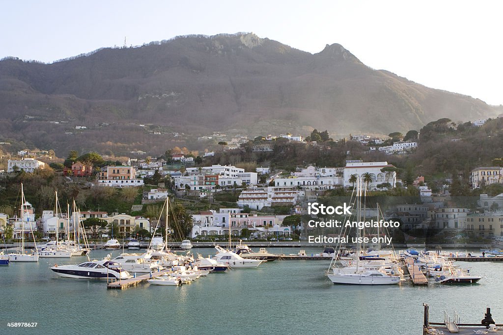 Casamicciola, Ischia Island, Bay of Naples, Italy. "Ischia, Italy - March 14, 2012: Casamicciola Harbur with sail boats and houses, photo taken at sunset from sea." Bay of Water Stock Photo