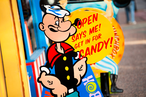 Halifax, Nova Scotia, Canada - May 28, 2012: The Freak Lunchbox candy store Popeye signage.  This sign and slogan is visible just outside the front entrance on Barrington Street in downtown Halifax.  Sidewalk visible in background.  Freak Lunchbox was founded in 2001 and has become an iconic location in downtown Halifax. The store sells unique and retro candy as well as toys, collectibles, and beverages. Currently (as of 2011) there are three locations with two in Nova Scotia and one in Saint John, New Brunswick, Canada.