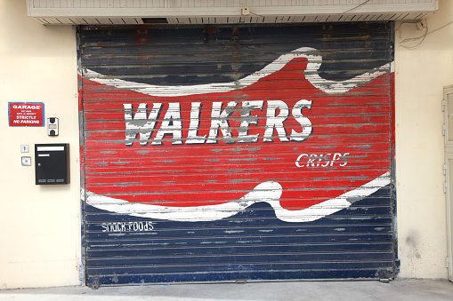 Buggiba, Malta  - December 8, 2012: An old yet colorful painted garage door advertises Walkers Crisps. 