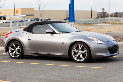 Bedford, Nova Scotia, Canada - April 11, 2012: Nissan 370Z Roadster in a parking lot with top up.  Retail stores in background and parking lot filled with cars.  The Nissan 370z is the sixth-generation of the Nissan Z-car replacing the 350z.