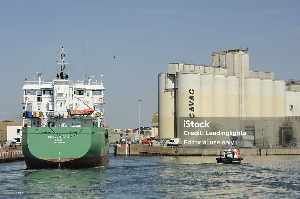 Arklow Faith at Les Sables-d'Olonne "Les Sables-d'Olonne, France - September 13, 2012: The Arklow Faith, an Irish registered, dry cargo ship entering a dock at Les Sables-d'Olonne,  Vend!AA>e, France. Ship is rated at 2998 gross tonnage and was built in 2006. Cargo exported from this port is mainly agricultural, particularly grain which is stored in dockside silos owned by Cavac, a farmers' co-operative enterprise. Pilot boat standing by. Unidentified crew." Adult Stock Photo