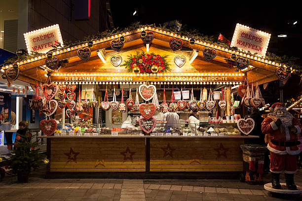 "Düsseldorf, Deutschland - 19. Dezember 2012: Lebkuchenstand auf dem Düsseldorfer Weihnachtsmarkt. Verkäufer, die Essen zubereiten und vorbeigehende Kunden."