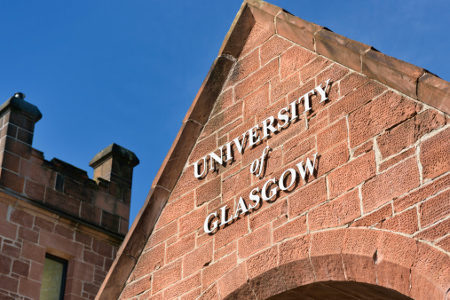 Glasgow, Scotland, UK - August 8, 2012: The sign for the University of Glasgow on the sandstone wall of the south gate entrance.