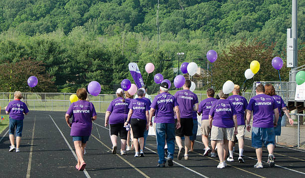 Cancer Walk "Nashville,Indiana, United States - May 18, 2012: Cancer Survivors- The American Cancer Society sponsers Relay for Life walks all over the country to raise money for cancer research. The survivors take the first lap around the track." walking for a cause stock pictures, royalty-free photos & images