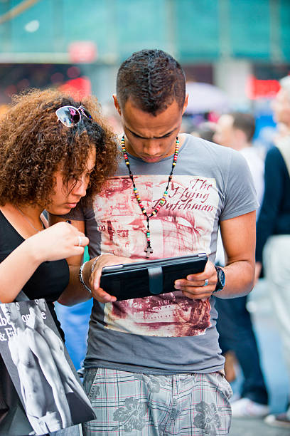 junges paar mit digitalen tablet am times square, new york - digital tablet travel destinations new york state times square stock-fotos und bilder