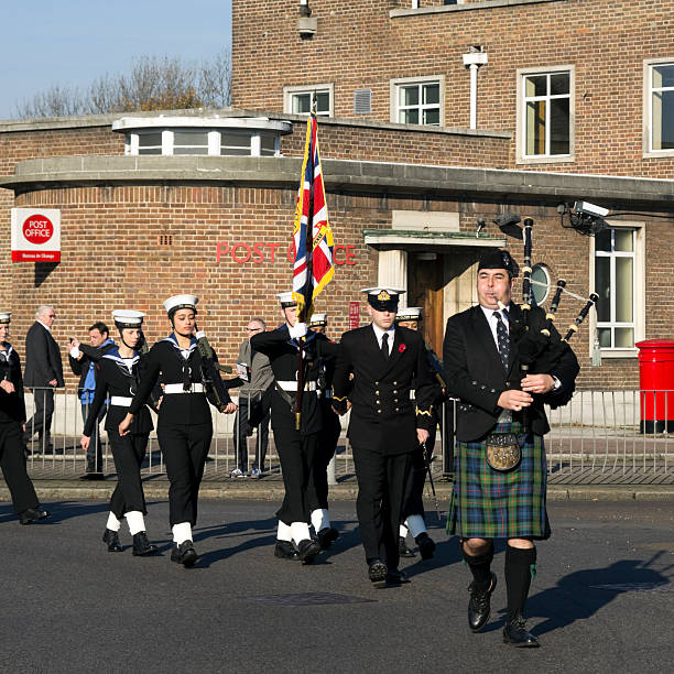 Royal Navy Cadets marching on Remembrance Sunday "Beckenham, England - November 13, 2011: A lone piper leading a procession of military cadets and officers to Beckenham war memorial on Remembrance Sunday. Seen here are some cadets representing the Royal Navy (the 'Senior Service', who always appear first). Further back are army cadets, RAF cadets and more navy cadets followed by contingents from local schools, scouts, guides, cubs and beavers, various church groups and many more organisations." tartan army stock pictures, royalty-free photos & images