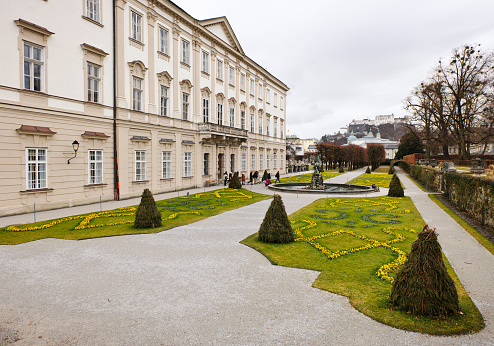 Salzburg, Austria - January 14, 2012: Visitors entering Mirabell Gardens from the Mirabell Palace, with the imposing Hohensalzburg Castle visible in the distance.
