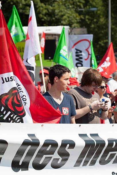 Protestors against Neonazi speech "Wiesbaden, Germany - July 27, 2012: Young counterprotestors against a meeting of Neonazis trying to disturb the speech campaign with whistles and many flags in the city center of Wiesbaden." national democratic party of germany stock pictures, royalty-free photos & images