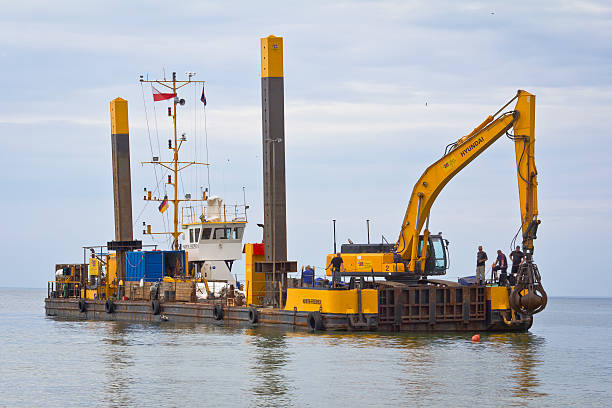 industrial chiatta con una macchina sul mare - industrial ship earth mover barge yellow foto e immagini stock