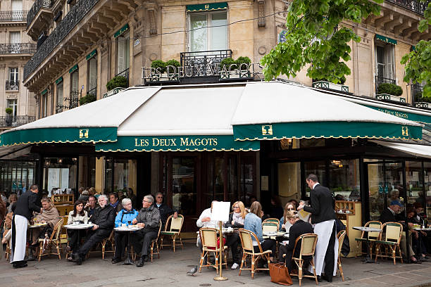 Cafe Les Deux Magots, Paris, France "Paris, France - April 27, 2012: Cafe Les Deux Magots.The cafe still trades on its reputation as the meeting place of the city's literary and intellectual elite. This derives from the patronage of Surrealist artists and writers including Ernest Hemingway in the 1920s and 1930s, and existentialist philosophers and writers in the 1950s.The cafe's name comes from the two wooden statues of Chinese commercial agents (magots) that adorn one of the pillars." hemingway house stock pictures, royalty-free photos & images