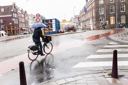 Amsterdam,The Netherlands - August 23, 2011: a man with a bicycle along the bike path in the city center of Amsterdam while it is raining.