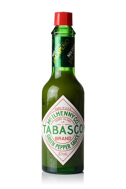ガラスのボトルタバスコ緑色のホットチリペッパーがけ - tabasco sauce ストックフォトと画像