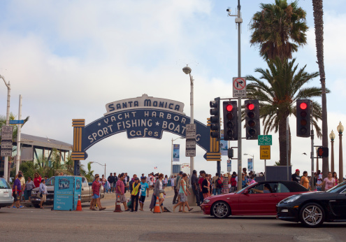 Santa Monica, Californai, USA - July 22, 2012: A A crowded Sunday afternoon in Santa Monica pier entrance and Ocean Avenue. People are walking to and from the pier. Santa Monica Pier entrance leads to the beach and to Pacific Park- an amusement park which is a famous location and a local landmark.