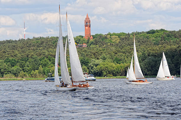 Sailing boat on Wannsee and Grunewald Tower (Berlin - Germany) "Berlin, Germany - May 28, 2012: teams in white sailing boat on lake wannsee in Berlin (Germany). In rural background the Grunewald Tower, made of brick stones at district of Teltow. From top of the tower people having a wonderful view over whole Wansee and Havel River" grunewald berlin stock pictures, royalty-free photos & images