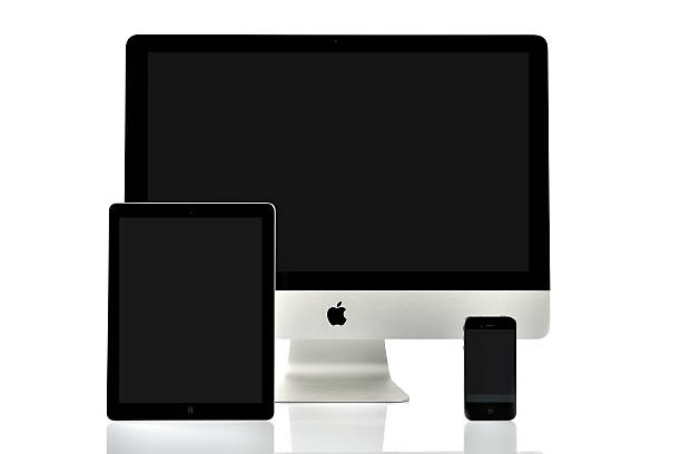 iMac, iPad and iPhone Kampen, The Netherlands - January 9, 2013: Apple iMac 21 inch computer, iPad second generation tablet and iPhone 4 mobile telephone isolated on a white background with a reflection in the foreground. All devices are turned off and have a blank black screen. apple device stock pictures, royalty-free photos & images