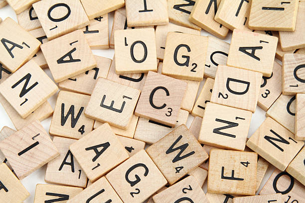 Scrabble letter tiles scattered in random order "West Palm Beach, USA - January 29, 2012: This is an image of Scrabble  letter tiles scattered in random order on a white background. Scrabble is a crossword strategy game distributed by Hasbro." word game stock pictures, royalty-free photos & images
