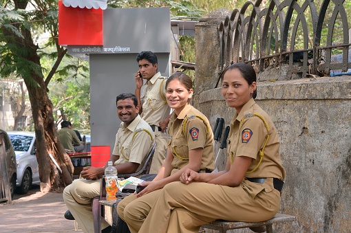 Mumbai, India - April 15, 2012: Four Police Officers on Malbar Hill in Mumbai smile at the camera as a group of tourist on an excursion approach them.