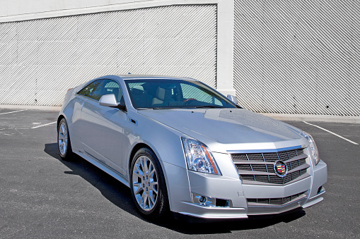 Nashville, USA - October 6th, 2010: A silver 2010 Cadillac CTS Coupe sports car in a parking lot in front of a modern wall.
